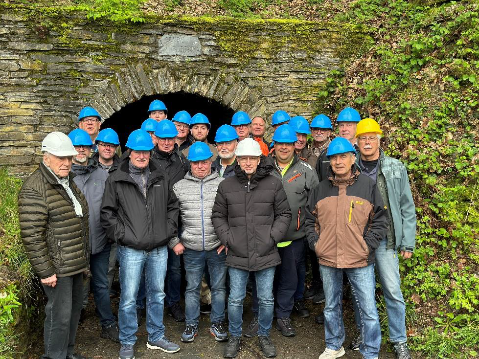 Gruppe von Männern mit Schutzhelmen vor dem historischen Göpelstollen bei einer bergbaulichen Exkursion der Bezirksgruppe Garzweiler